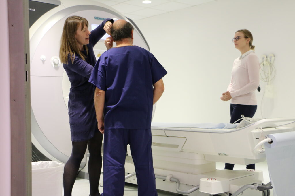 Research participant preparing for an MRI scan with two staff members