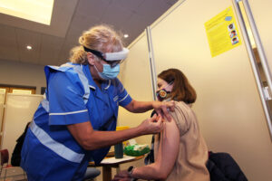 A women being given a covid vaccination by a nurse