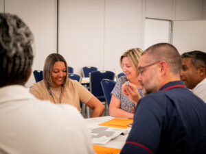 Close up of three men and women talking around a table and smiling