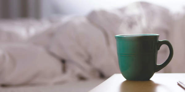 Photo of a bed and a cup of tea.