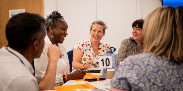 Five men and women sitting around a table chatting and smiling